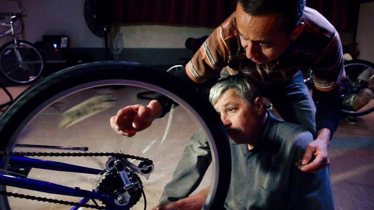 Angel Sacta, top, helps Javier Toro with bicycle repair during...