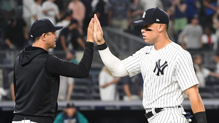 Yankees' Aaron Judge high fives with manager Aaron Boone after...