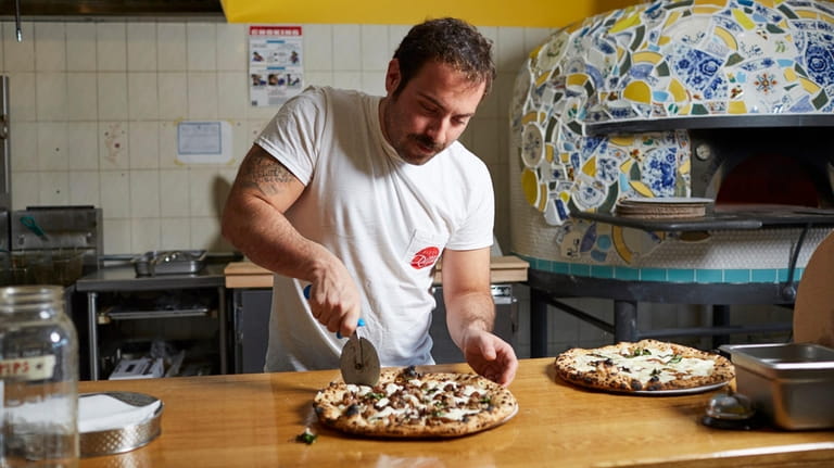 Jeff Marrone cuts a "Cannolo" pie topped with mozzarella, ricotta,...
