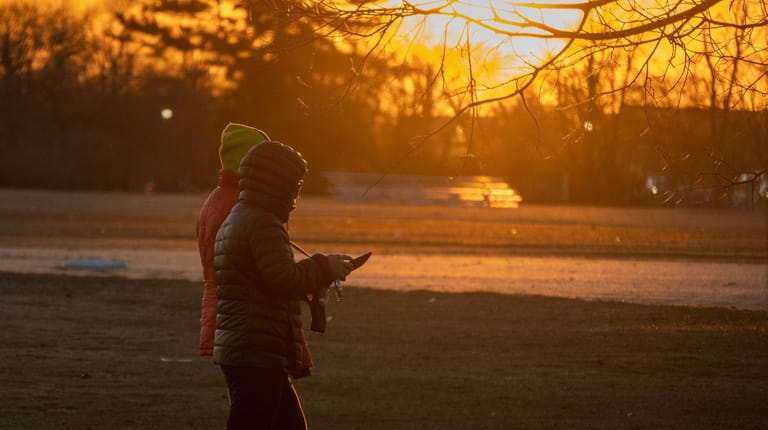 Strollers walk in Eisenhower Park in East Meadow at sunset Friday.