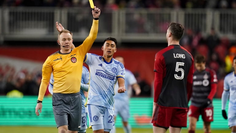 Referee Scott Bowman, left, shows a yellow card to Toronto...