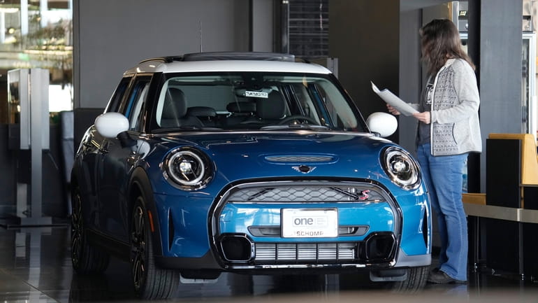 A potential buyer looks over a 2023 Cooper S sedan...
