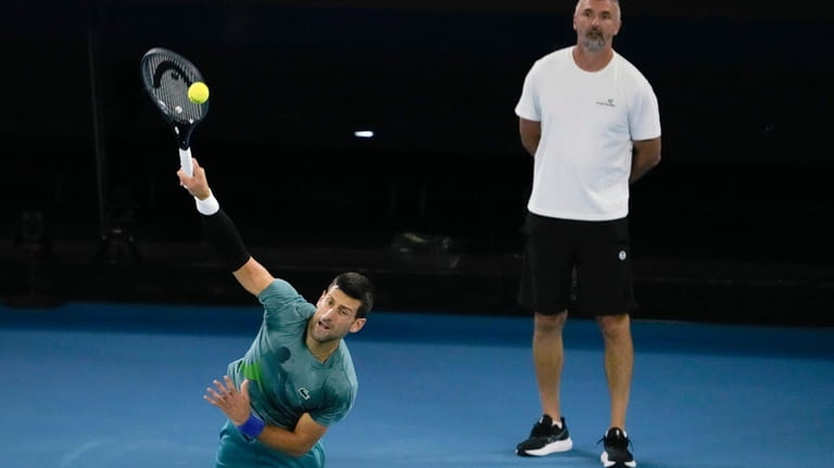 Serbia's Novak Djokovic serves as his coach Goran Ivanisevic watches...
