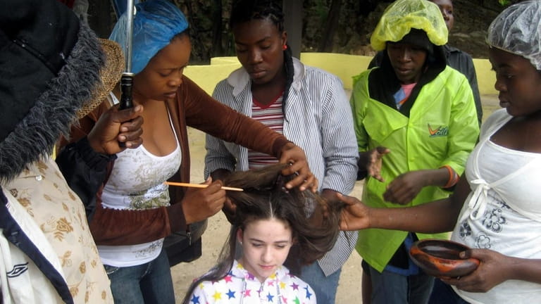 Kidsday reporter Laura Fallick gets her hair braided by Haitians...