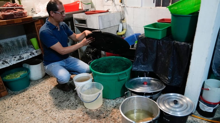 Restaurant owner Luis Alirio Soler shows buckets of water while...