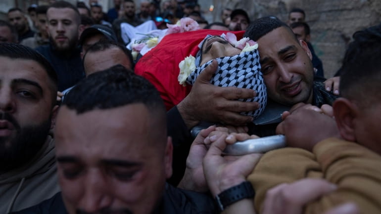 Palestinian mourners carry the body of Ali Alqam, 32, during...