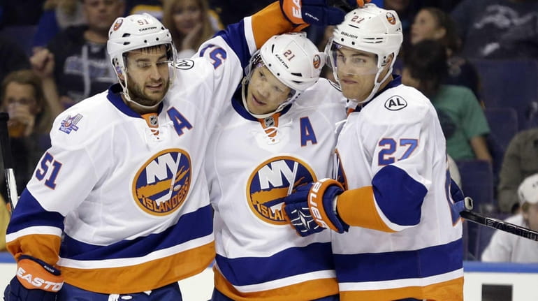 New York Islanders' Kyle Okposo, center, is congratulated by teammates...