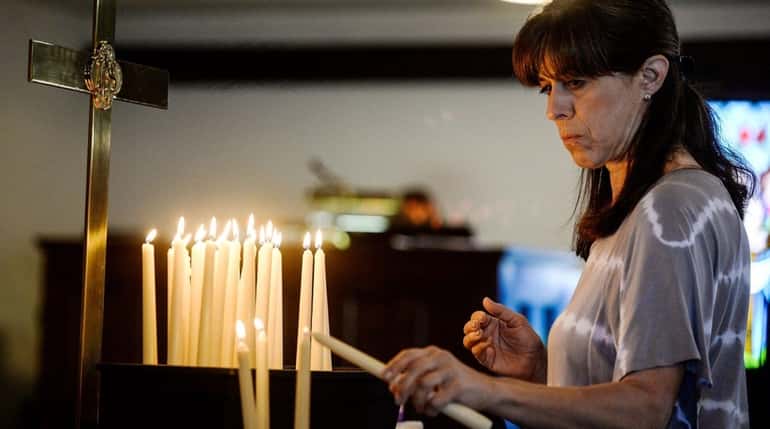 Susan Oldis of Rockville Centre lights a candle Sunday, June...