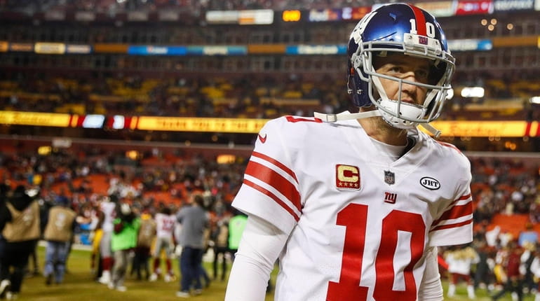 Giants quarterback Eli Manning walks off the field after a...