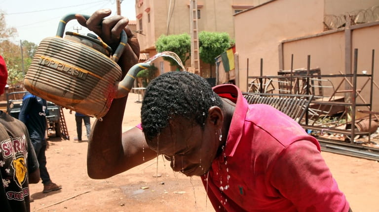 Soumaila Traoré, a 30-years-old welder, cools off with water under...