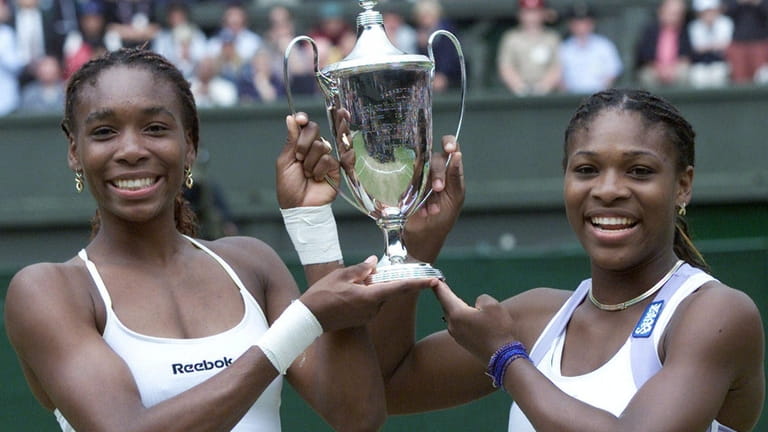Venus, left, and Serena Williams hold their trophy after winning...