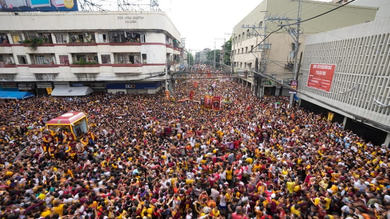 A glass-covered cart carrying the Black Nazarene makes its way...