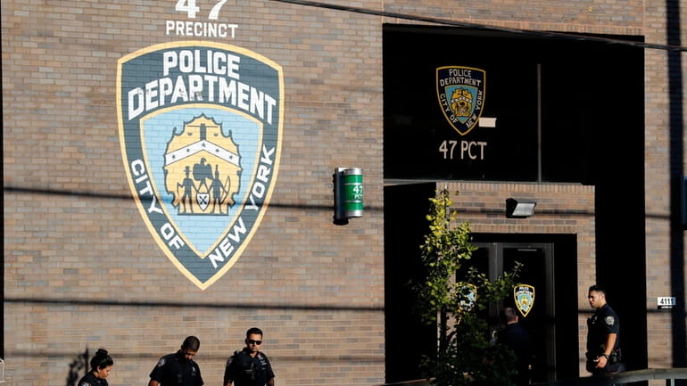 Police officers stand in front of the 47th precinct in...