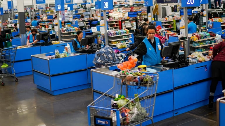 Cashiers process purchases at a Walmart Supercenter in North Bergen,...