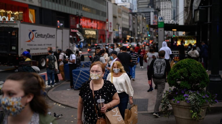 Pedestrians wearing face masks walk along a Manhattan street. New York...