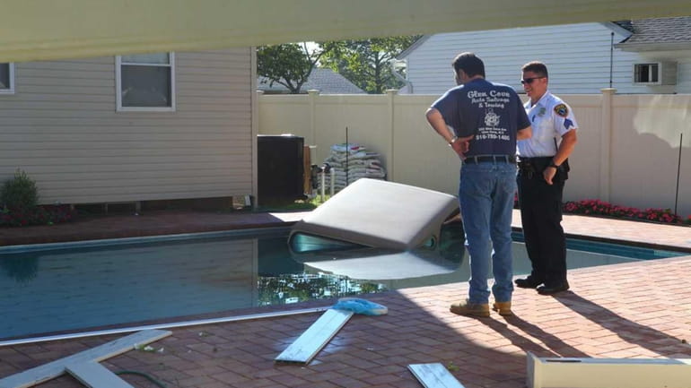 A Jeep sits in a pool after crashing through a...