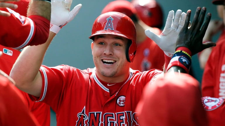 Mike Trout is greeted in the dugout after hitting a...