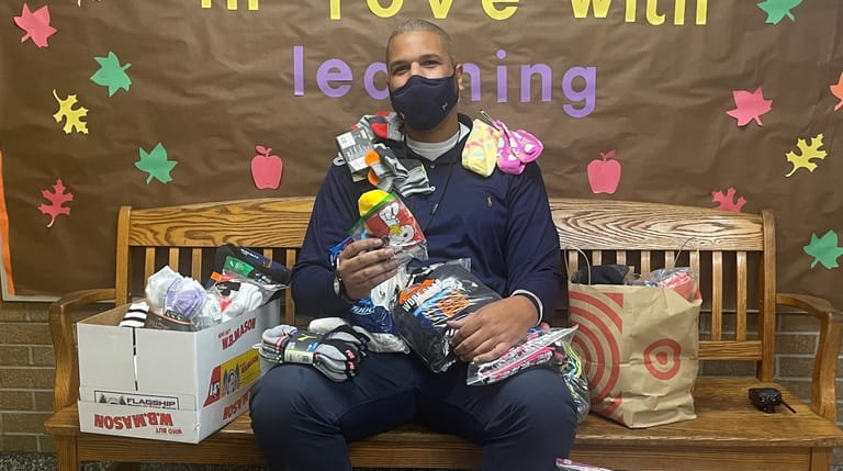 School social worker Jarrod Alexander poses with 100 pairs of...