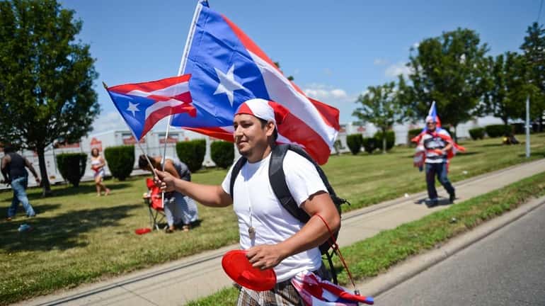 Johnny Castro, of Brentwood, walks down Fifth Avenue holding Puerto...