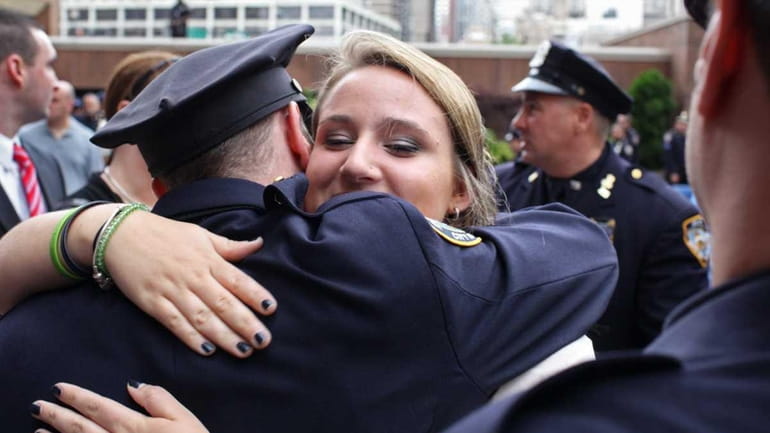 Caitlyn Figoski is hugged by members of the 75th Precinct,...