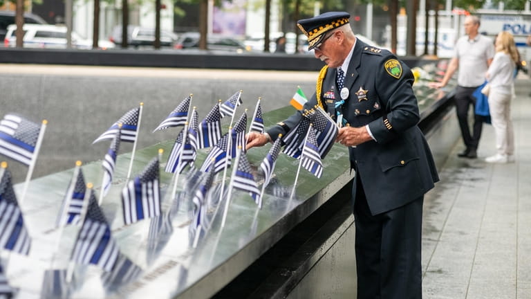 Sam Pulia, a retired firefighter from Westchester, Illinois, places flags...