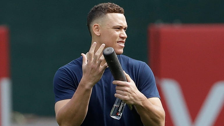 Yankees' Aaron Judge gestures toward teammates before a baseball game...