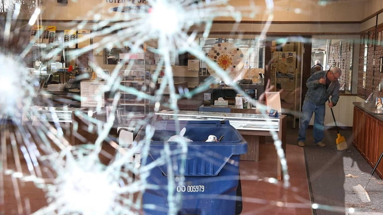 A worker cleans up glass at a business that was...