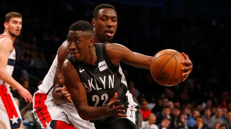 The Nets' Caris LeVert drives against the Wizards' Ian Mahinmi...