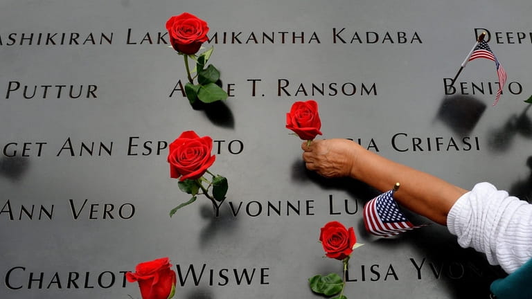 A woman places flowers in the inscribed names along the...