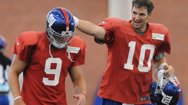 Giants starting quarterback Eli Manning, right, gives a pat on...