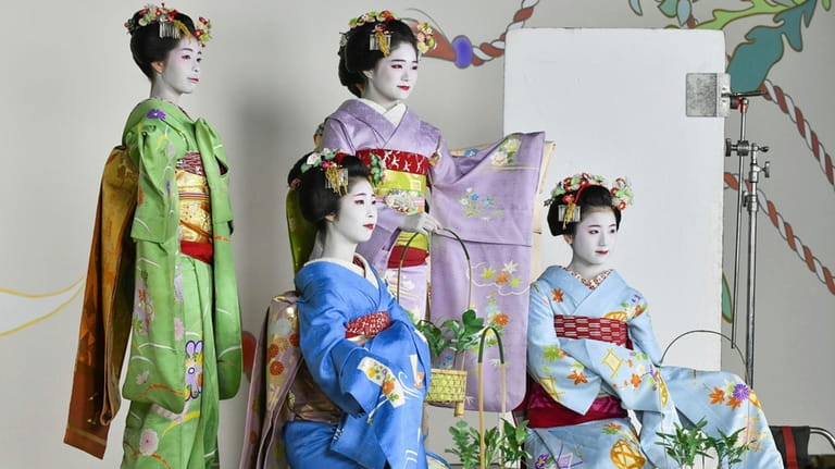 Maiko, or apprentice geiko, pose for photos ahead of the...