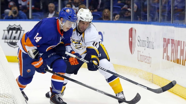 Thomas Hickey of the Islanders defends against Eric Nystrom of...