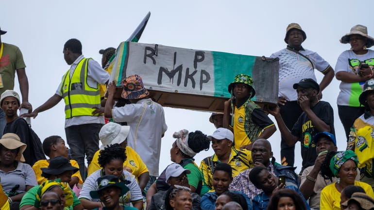 African National Congress supporters carry a mock coffin of former...