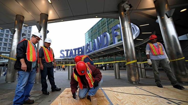 Metropolitan Transit Authority workers lay plywood over subway grates at...