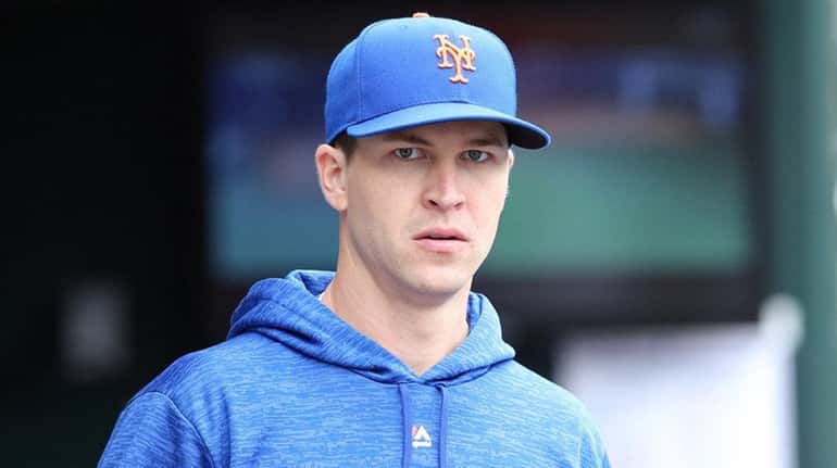 Mets starting pitcher Jacob deGrom looks on during a game...