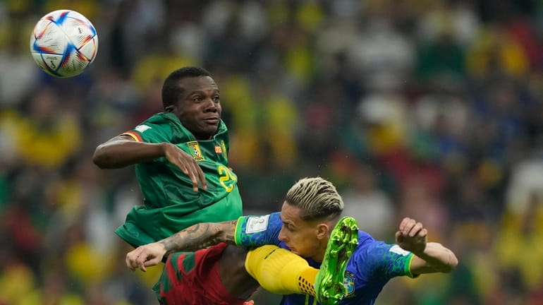 Cameroon's Tolo Nouhou, left, jumps to a ball with Brazil's...