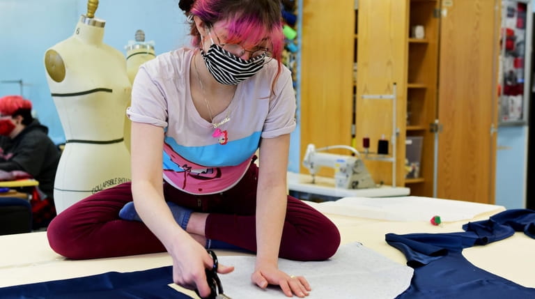 Samantha Claude, a student at Center Moriches High School, cuts fabric...