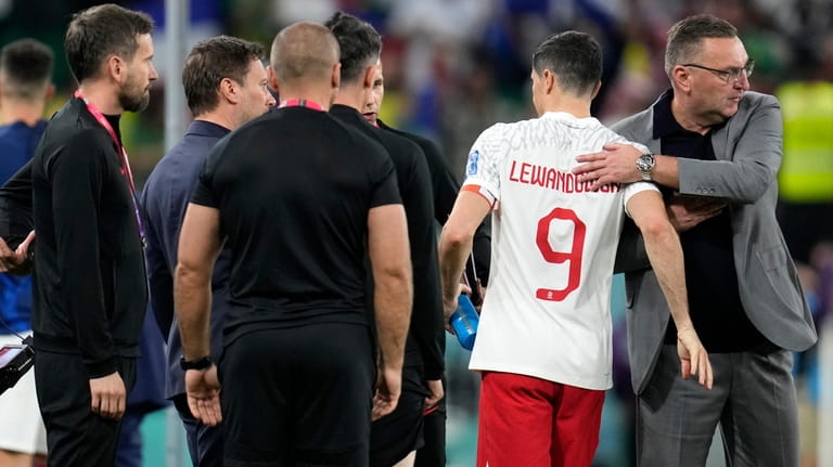 Poland's head coach Czeslaw Michniewicz, right, embraces Robert Lewandowski (9)...
