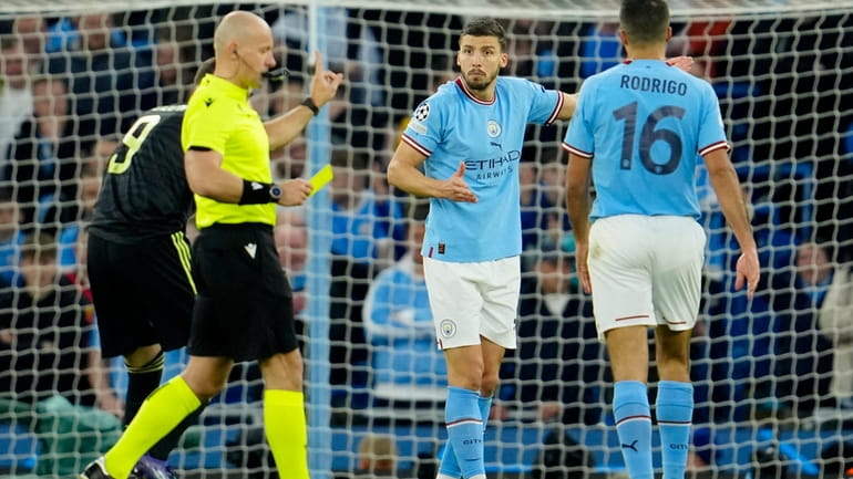 Referee Szymon Marciniak shows a yellow card to Manchester City's...