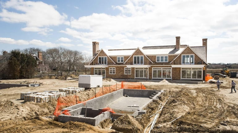 Construction workers build an 8,600-square-foot, nine-bedroom spec home being built...