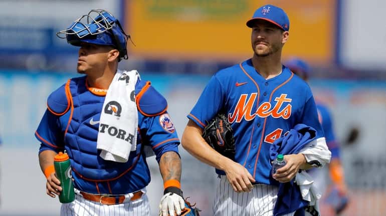 Mets catcher Wilson Ramos, left, and pitcher Jacob deGrom walk...