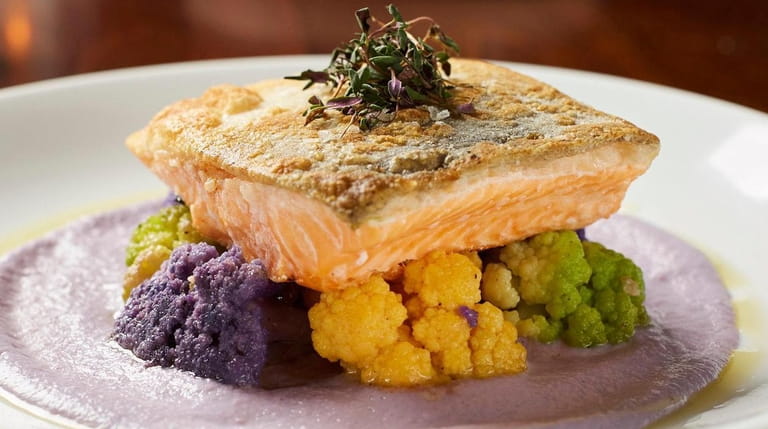 Pan-seared Arctic char rests on a bed of multicolored cauliflower,...