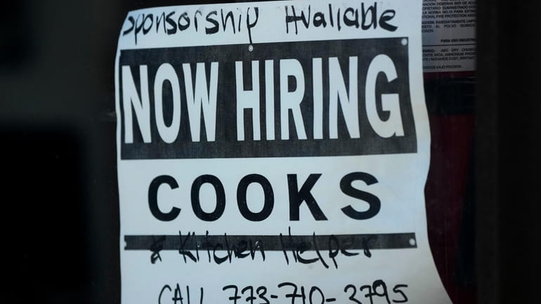 A hiring sign is displayed at a restaurant in Chicago,...