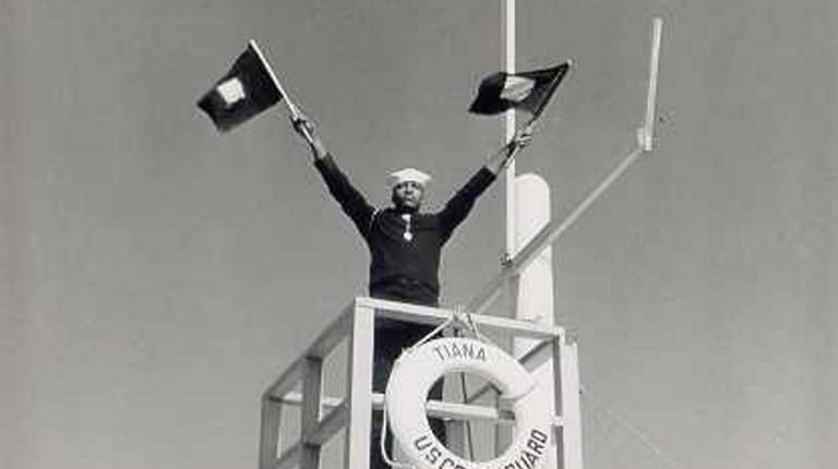 A Coast Guardsman semaphores at Station Tiana during its activation...