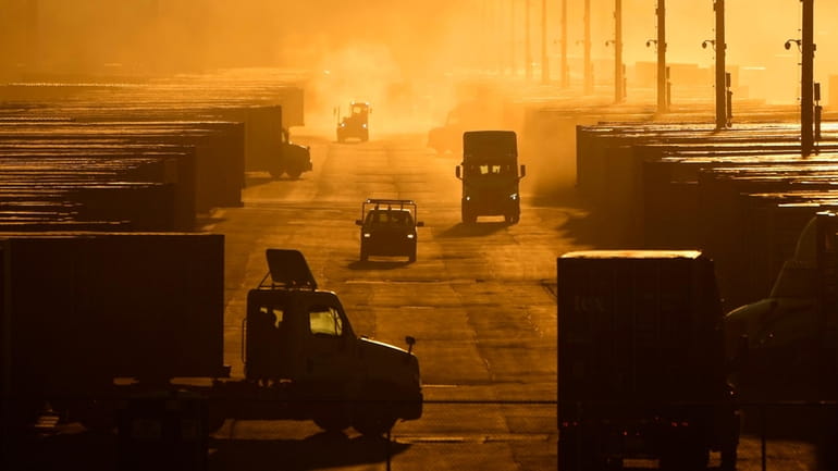 Workers drive among shipping containers and trailers at a BNSF...