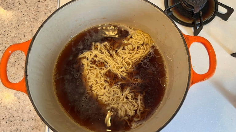 A ramen noodled is added to the soup being cooked...