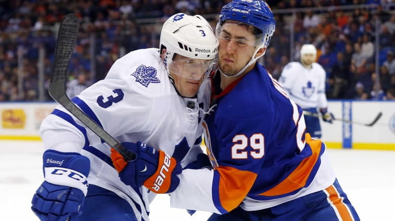 Brock Nelson of the Islanders defends against Dion Phaneuf of...