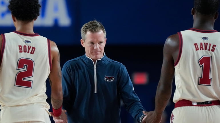 Florida Atlantic head coach Dusty May claps hands with guards...