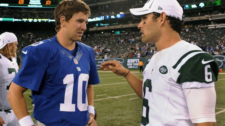 Giants quarterback Eli Manning, left, speaks with Jets quarterback Mark...