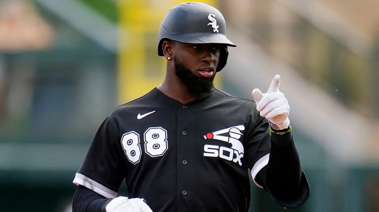 The White Sox's Luis Robert points to teammates in the...